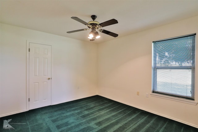 unfurnished room with ceiling fan and dark carpet