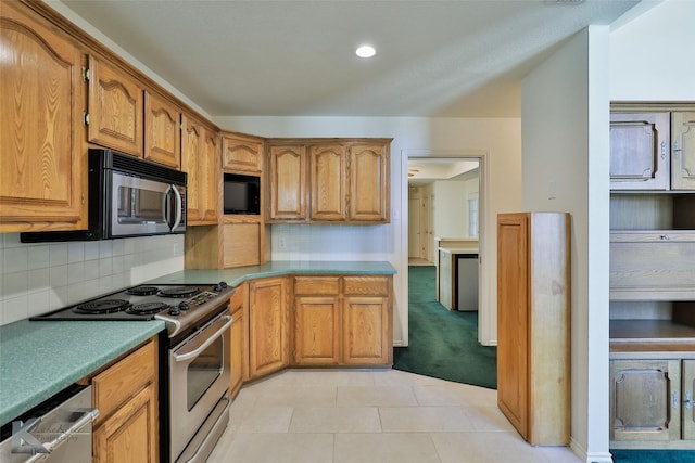 kitchen with light tile patterned floors, appliances with stainless steel finishes, and tasteful backsplash