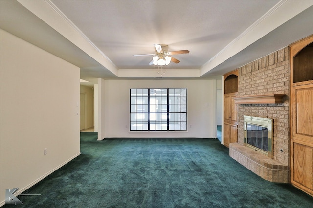 unfurnished living room with a fireplace, a tray ceiling, dark carpet, and ornamental molding