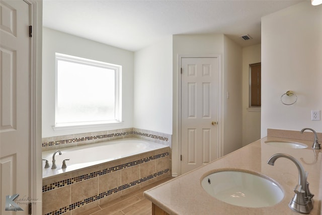 bathroom featuring hardwood / wood-style floors, vanity, and tiled tub