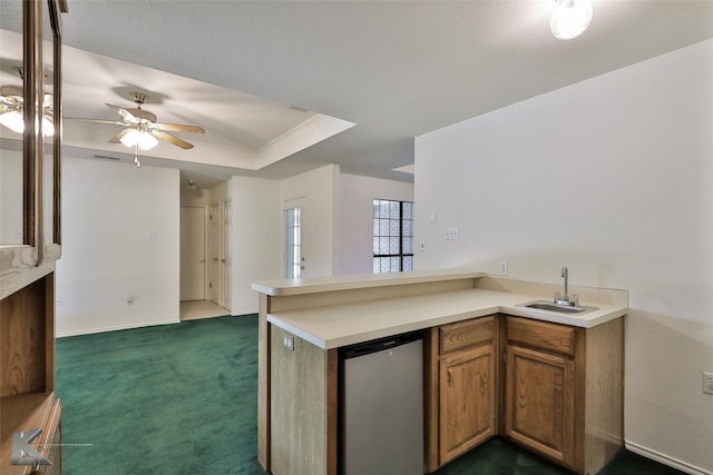 kitchen featuring ceiling fan, sink, dark colored carpet, stainless steel dishwasher, and kitchen peninsula