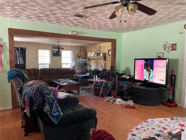 living room featuring a textured ceiling, ceiling fan with notable chandelier, and hardwood / wood-style flooring