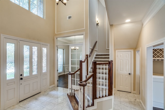 entryway with ornamental molding, light wood-type flooring, plenty of natural light, and a towering ceiling