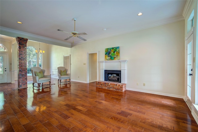 unfurnished living room with a brick fireplace, decorative columns, ornamental molding, and wood finished floors