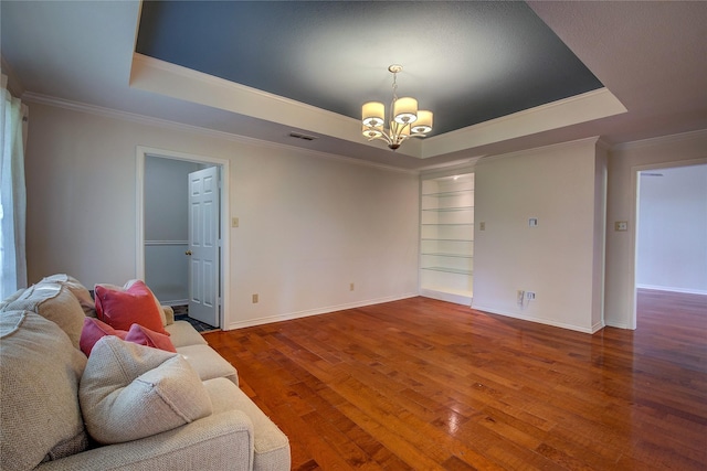 living area featuring a raised ceiling, baseboards, a notable chandelier, and hardwood / wood-style floors