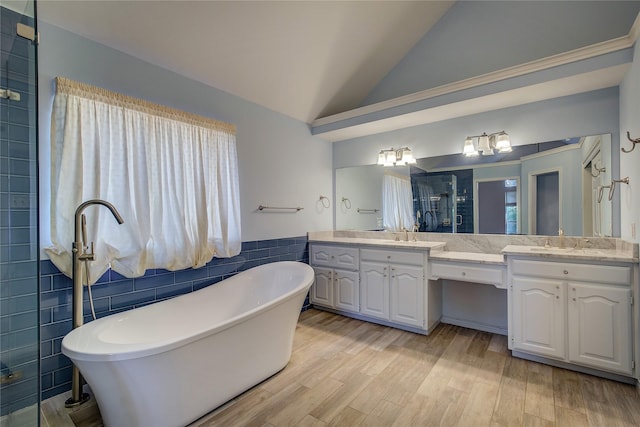 full bathroom with lofted ceiling, wood finished floors, a sink, a shower stall, and tile walls