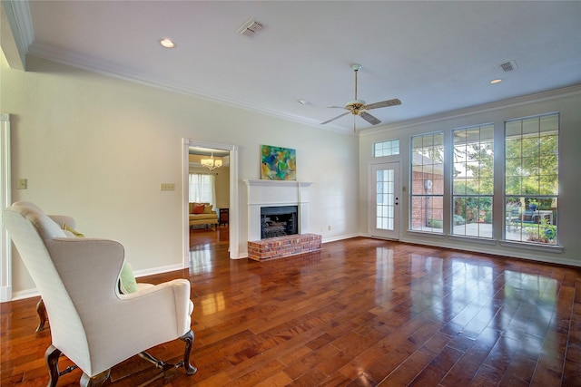 living room featuring ornamental molding, a brick fireplace, visible vents, and wood finished floors