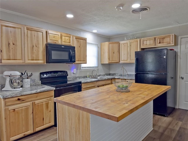 kitchen with light wood-type flooring, crown molding, butcher block counters, black appliances, and a center island