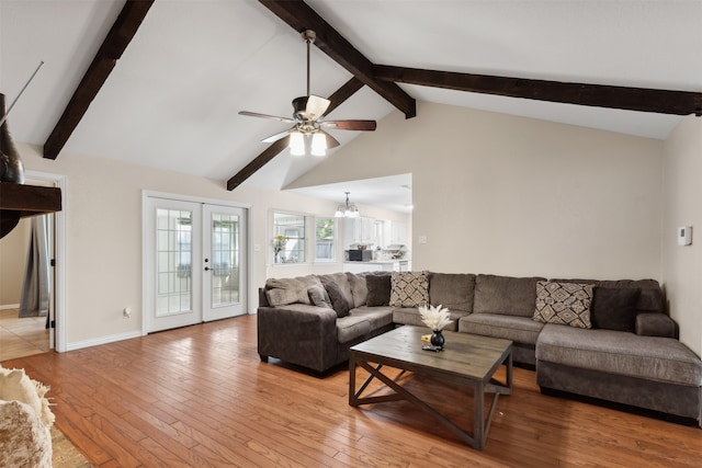 living room with ceiling fan with notable chandelier, french doors, light hardwood / wood-style floors, and vaulted ceiling with beams