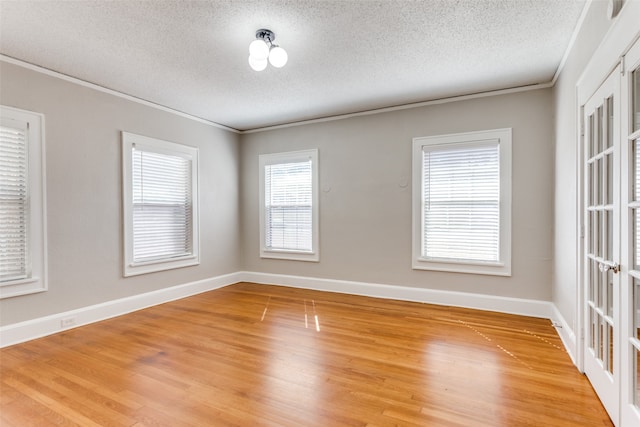 spare room featuring french doors, crown molding, hardwood / wood-style floors, and a textured ceiling