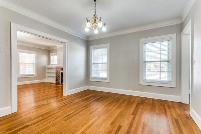 unfurnished room with plenty of natural light, an inviting chandelier, wood-type flooring, and ornamental molding