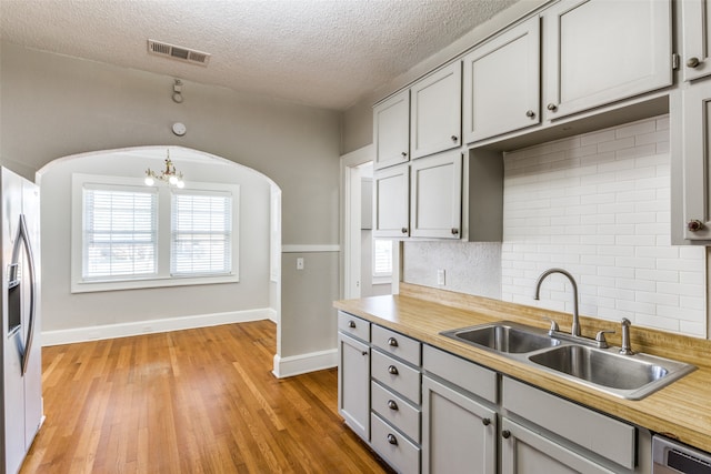 kitchen with gray cabinetry, decorative backsplash, sink, and light wood-type flooring