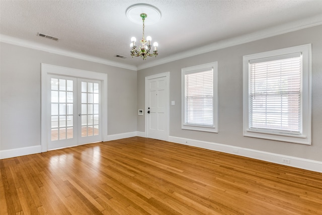 spare room featuring crown molding, an inviting chandelier, a textured ceiling, and hardwood / wood-style flooring