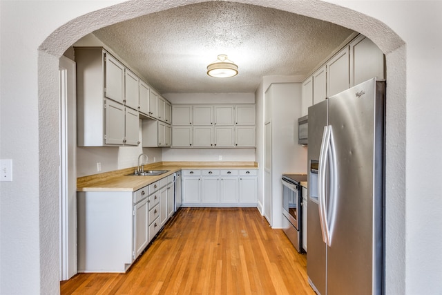 kitchen with light wood-type flooring, butcher block counters, sink, and appliances with stainless steel finishes