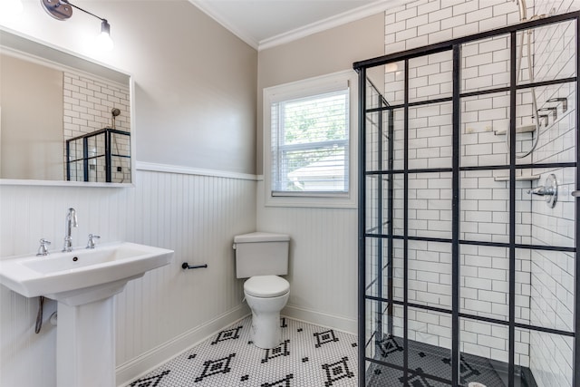 bathroom featuring tile patterned floors, ornamental molding, a tile shower, sink, and toilet