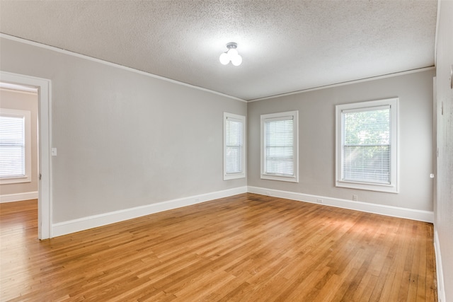 spare room with ornamental molding, a textured ceiling, and light wood-type flooring