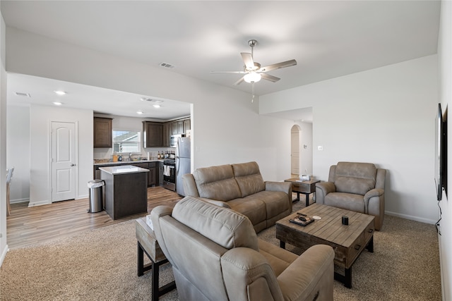 living room with ceiling fan, sink, and light hardwood / wood-style floors