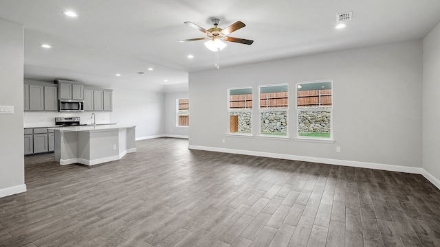 unfurnished living room featuring dark hardwood / wood-style floors, sink, and ceiling fan