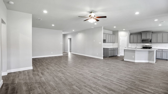 unfurnished living room with ceiling fan, sink, and hardwood / wood-style floors