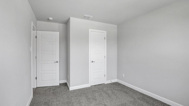 unfurnished bedroom featuring dark carpet and a closet