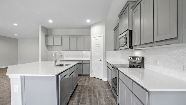 kitchen with a kitchen island with sink, stainless steel appliances, sink, and dark hardwood / wood-style flooring