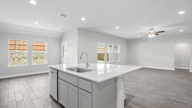 kitchen with an island with sink, light wood-type flooring, sink, and stainless steel dishwasher