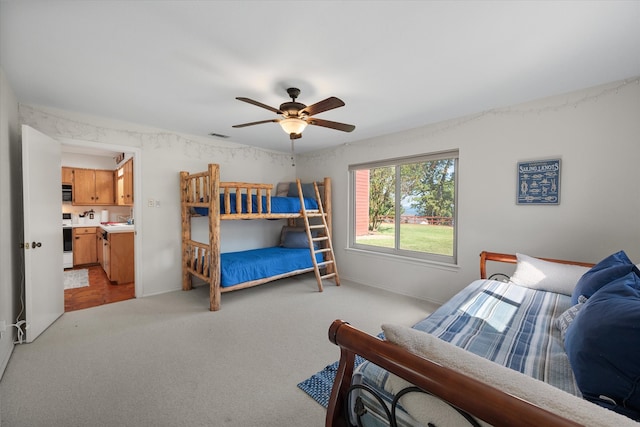 bedroom with connected bathroom, ceiling fan, and light carpet