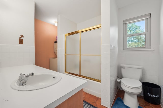 full bathroom featuring toilet, enclosed tub / shower combo, tile walls, vanity, and tile patterned flooring