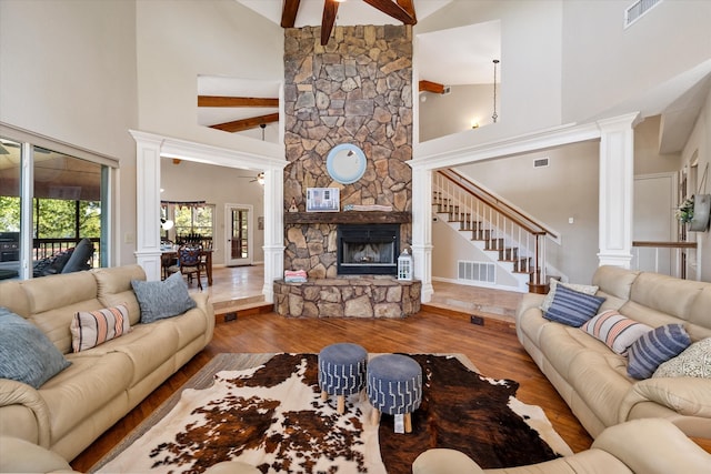 living room with a stone fireplace, hardwood / wood-style flooring, high vaulted ceiling, and ceiling fan