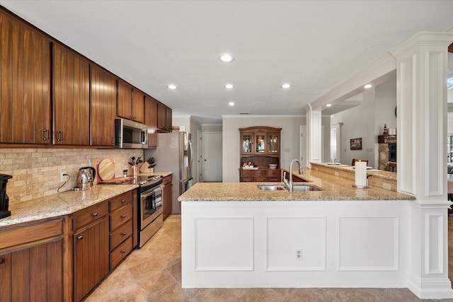 kitchen with kitchen peninsula, backsplash, light stone countertops, sink, and stainless steel appliances