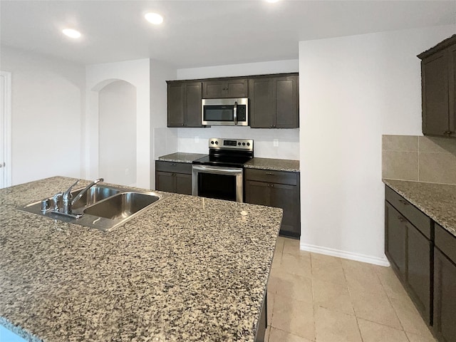 kitchen featuring an island with sink, dark brown cabinetry, sink, and stainless steel appliances