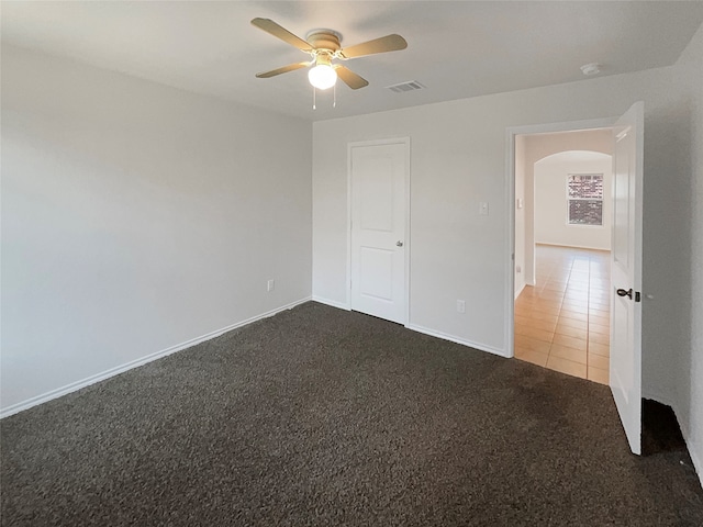 unfurnished bedroom with dark colored carpet and ceiling fan