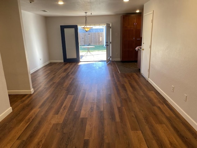 spare room with visible vents, baseboards, and dark wood-type flooring