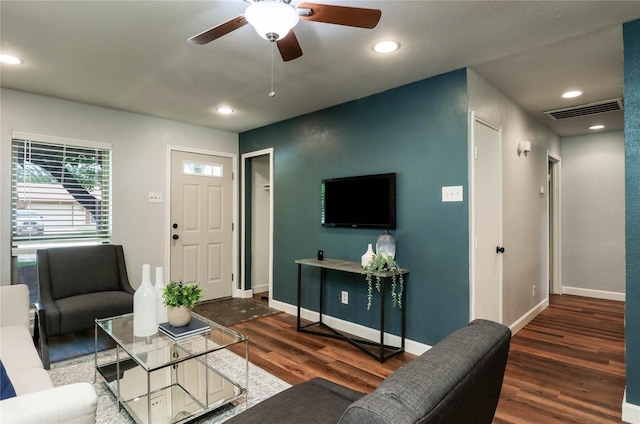 living room featuring dark wood-style floors, baseboards, and visible vents