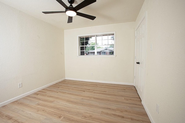 empty room with a ceiling fan, a textured wall, baseboards, and wood finished floors