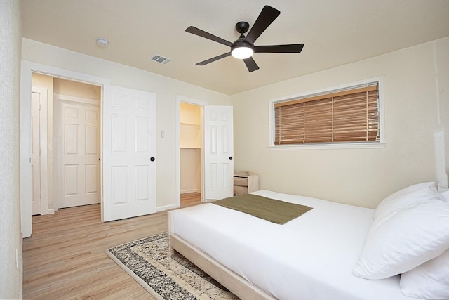 bedroom featuring a spacious closet, light hardwood / wood-style floors, a closet, and ceiling fan