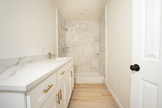 bathroom featuring vanity, hardwood / wood-style floors, and tiled shower