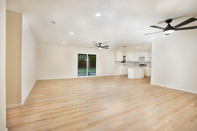 unfurnished living room featuring ceiling fan, a textured ceiling, and light wood-type flooring