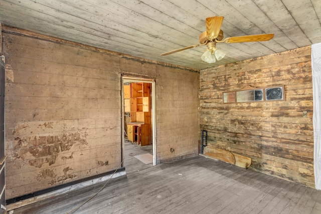 spare room featuring ceiling fan, wood walls, wooden ceiling, and dark wood-type flooring