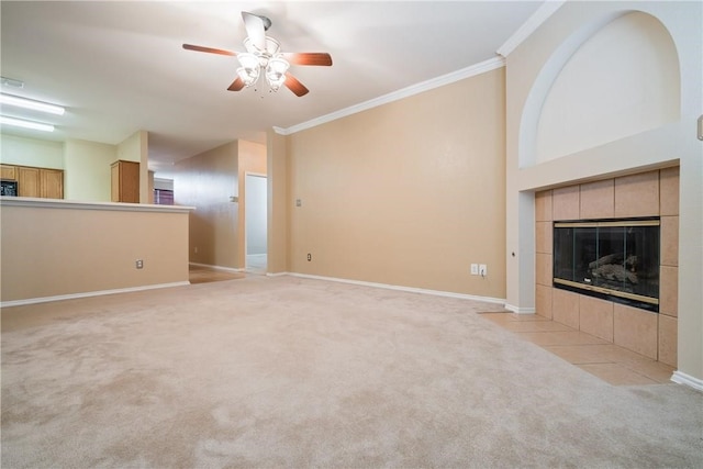 unfurnished living room with crown molding, a tiled fireplace, light colored carpet, and ceiling fan