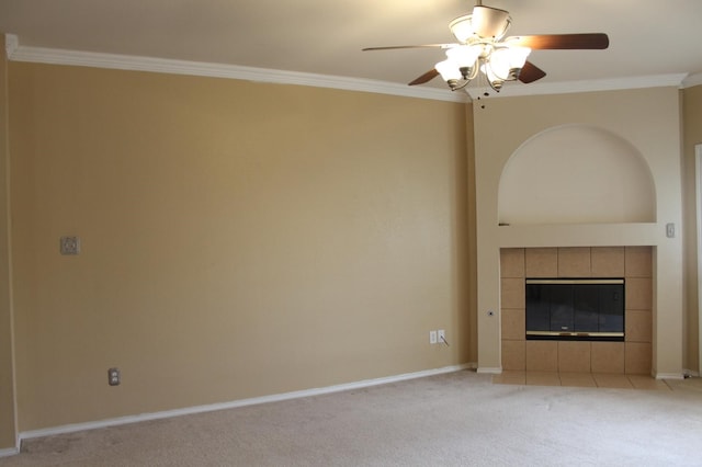 unfurnished living room featuring ceiling fan, crown molding, a tile fireplace, and light colored carpet