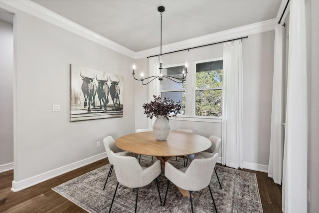 dining room featuring dark wood-type flooring, a chandelier, crown molding, and baseboards