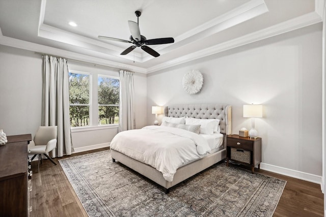 bedroom with a tray ceiling, ceiling fan, dark hardwood / wood-style flooring, and crown molding