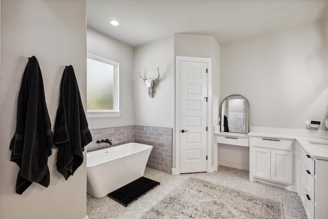 bathroom with a freestanding tub, vanity, a closet, tile patterned floors, and carpet