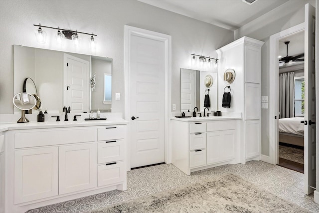 bathroom featuring a sink, ceiling fan, two vanities, and ensuite bath