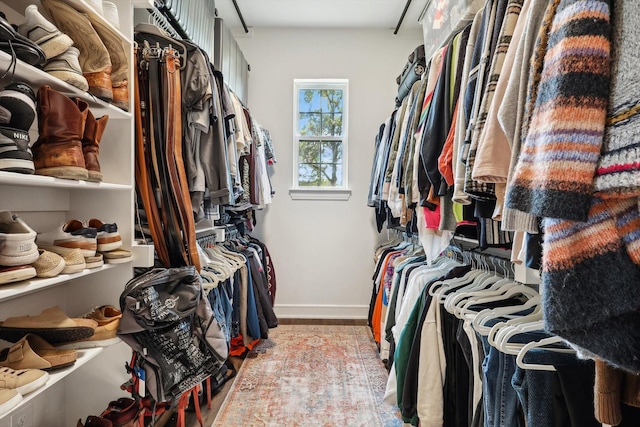 walk in closet with light wood finished floors