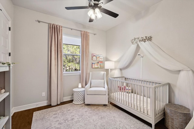 bedroom with ceiling fan, wood-type flooring, and a crib