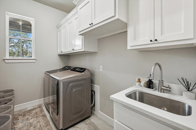 clothes washing area featuring washer and dryer, cabinets, and sink