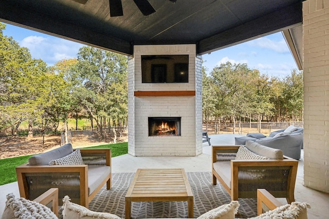 view of patio / terrace featuring an outdoor living space with a fireplace, fence, and a ceiling fan