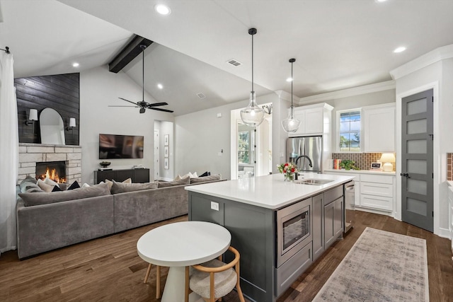 kitchen featuring white cabinetry, open floor plan, light countertops, appliances with stainless steel finishes, and an island with sink